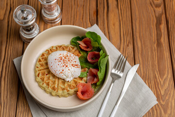 Potato-squash waffles with poached egg, sprinkled with smoked paprika, lettuce leaves and salted salmon