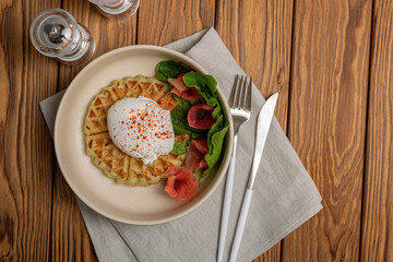 Potato-squash waffles with poached egg, sprinkled with smoked paprika, lettuce leaves and salted salmon
