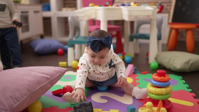 Teacher and preschool students playing with toys sitting on floor at kindergarten