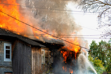 Fire quickly destroys residential building. Firefighters trying to put out big fire. - obrazy, fototapety, plakaty