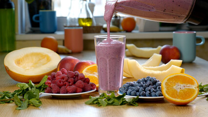 Raspberry Blueberry Melon Smoothie is poured into a glass on the background of fresh fruits
