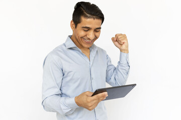 Successful man with tablet. Indian man in blue shirt celebrating victory with clenched fist. Portrait, studio shot, technology, success concept