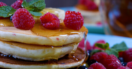 Pancakes with raspberry, banana and a mint leaf and honey