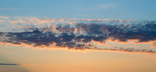 Sunset on sky with bright clouds. Wide photo.