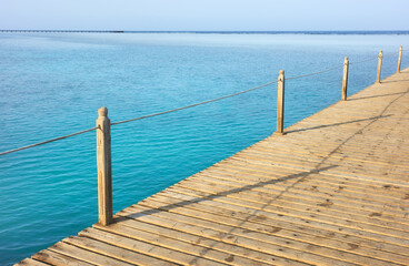 Wooden pier with rope railing, selective focus.