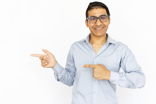 Happy man pointing aside. Indian man in blue shirt showing product or app. Portrait, studio shot, advertising concept