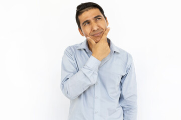 Handsome man thinking hard while standing on white background. Pensive Hispanic man touching his...