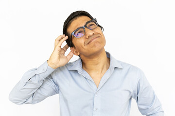 Pensive man scratching head. Indian man in blue shirt looking up and thinking. Portrait, studio...