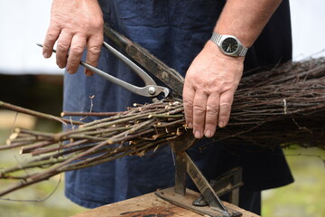 Der Besenmacher. Detail eines Mannes bei der Herstellung von Reisigbesen