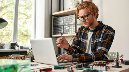 Concentrated male IT engineer looking at microchip