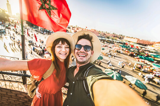 Happy tourists couple visiting Jamaa el-Fna market Marrakech, Morocco - Boyfriend and girlfriend taking selfie picture on summer vacation - Holidays and tourism concept