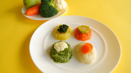 baby food vegetable puree shaped on yellow dish