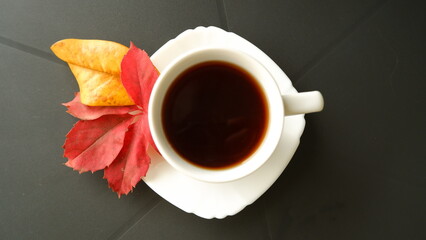 Autumn cup of tea on table, yellow and red fallen leaves, autumn drink, mood and comfort concept