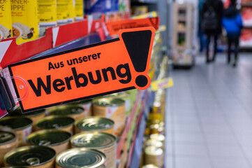Werbung in einem Supermarkt mit einem Schild und dem Text "Aus unserer Werbung" in deutscher Sprache