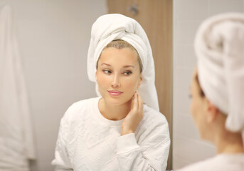 Woman looking in the mirror Applying the cream..Magic anti-aging cream...