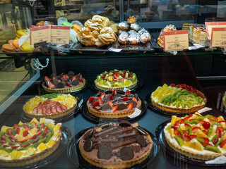Shop shelves. Cakes and goodies. Cake stand. Fruit and cream. Assortment in the supermarket. Unhealthy food. Products with sugar.