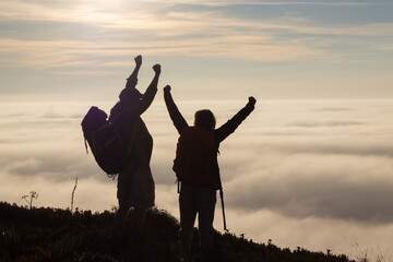 Excited family hiking on summer. Man and woman in casual clothes and with ammunition celebrating reaching peak. Hobby, active lifestyle concept