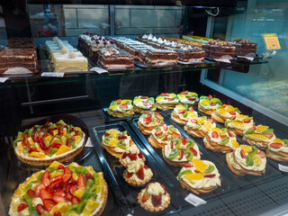 Shop shelves. Cakes and goodies. Cake stand. Fruit and cream. Assortment in the supermarket. Unhealthy food. Products with sugar.