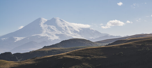 Evening panorama of Mount Elbrus from two peaks with snow and glaciers, in cloudless autumn weather