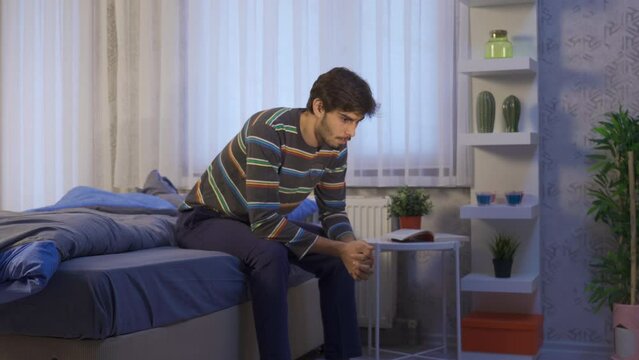 Thoughtful unhappy young man feeling restless in his room.
Stressed young man cannot sleep because he is thinking and restless.
