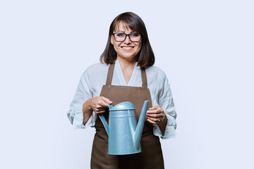 Portrait of woman in apron with watering can in hands on white background