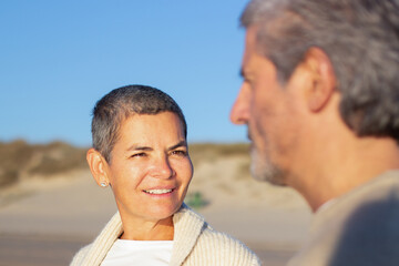 Smiling short-haired senior lady looking at her husband while couple spending time together on...