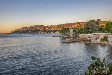 Fototapeta premium Paysage en bord de mer dans la baie de Villefranche sur Mer sur la Côte d'Azur, lieu de villégiature, dans les rayons du soleil levant