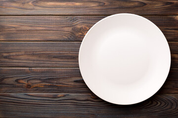 Top view of empty light plate on wooden background. Empty space for your design