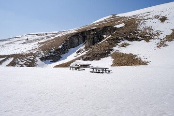 Winter view of wooden benches and tables in front of impressive cave  hidden in the snow - 549317455