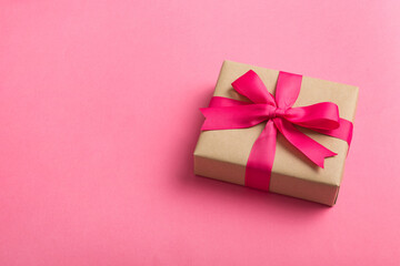 Wrapped christmas or other holiday handmade present in craft paper with colored ribbon. Present box, decoration of gift on table, top view with copy space