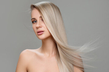 Portrait of a beautiful woman with long straight hair and makeup. Flying blonde hair - obrazy, fototapety, plakaty