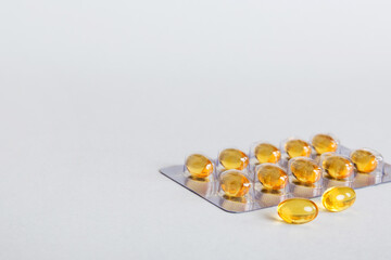 Blister package with fish oil capsules on color background. Medicine pills on a light background....