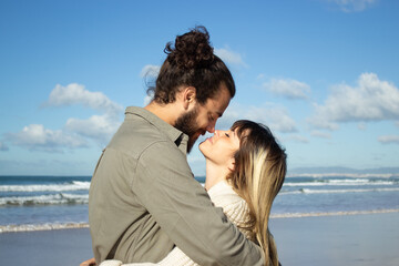 Fototapeta premium Caucasian couple on summer vacation. Bearded man and woman with fair hair looking at each other, touching with noses tenderly. Love, vacation, affection concept