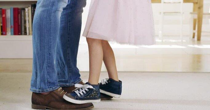 Dance, father and child dancing holding hands with happy daughter or kid standing on dads shoes at home. Family, papa and young girl moving to music or love song with princess stepping on mans feet