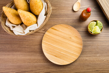 Chicken Coxinha, known as Coxinha in Brazil. Served in the basket, with spices such as lemon and pepper on the side. Wooden table in the background. Traditional brazilian snack Selective focus.