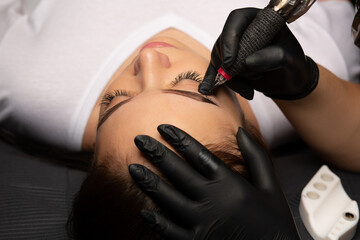 Cosmetology master's hand doing permanent makeup