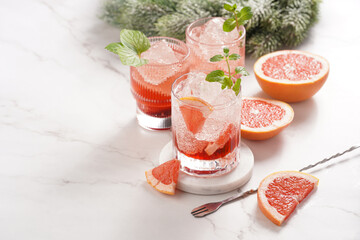 Preparation of a grapefruit alcohol free cocktail - several tumbler glasses with ice cubes on...