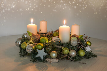 Second Advent, wreath with two burning white candles and green Christmas decoration on a table,...