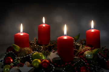 Candle light in the night, part of an Advent wreath with four red candles and Christmas decoration...