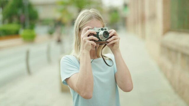 Young blonde woman tourist using vintage camera at street