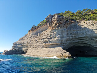 Fototapeta na wymiar 22 Oct 2022, Kemer, Antalya, Turkey. Boat trip, close to the cliff with a cave inside. Cave is called Pirate Cave. Plans on top of the cliff, blue sea, birds, blue sky, perfect landscape.