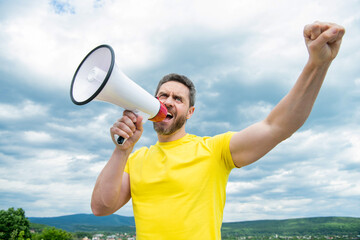 man in yellow shirt shout in loudspeaker on sky background. propaganda