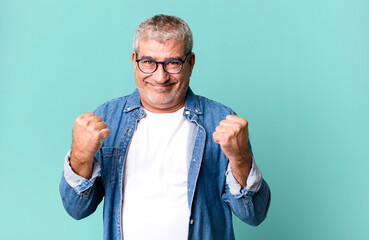 middle age senior man shouting triumphantly, laughing and feeling happy and excited while...