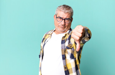 middle age senior man feeling cross, angry, annoyed, disappointed or displeased, showing thumbs...