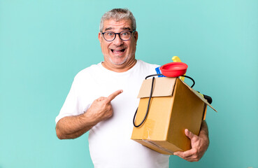 middle age senior man looking excited and surprised pointing to the side. housekeeper repairman with a toolbox concept