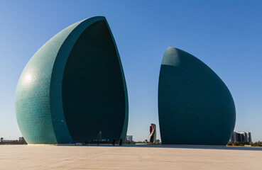 Baghdad, Iraq - November 2022: Split turquoise domes of Al Shaheed war memorial also called as Martyr's monument at the centre of the two half-domes is the Iraqi flag - obrazy, fototapety, plakaty
