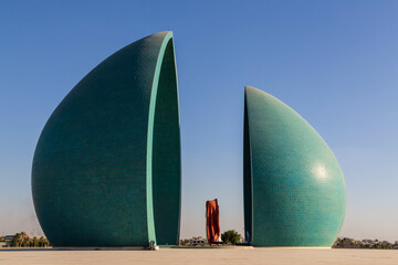 Baghdad, Iraq - November 2022: Split turquoise domes of Al Shaheed war memorial also called as Martyr's monument at the centre of the two half-domes is the Iraqi flag - obrazy, fototapety, plakaty