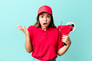 hispanic pretty woman feeling extremely shocked and surprised. packer and delivery employee