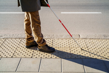 Tactile tiles in the city. Close-up of a blind man with a cane