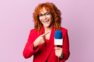 red hair pretty woman looking excited and surprised pointing to the side. journalist and presenter...